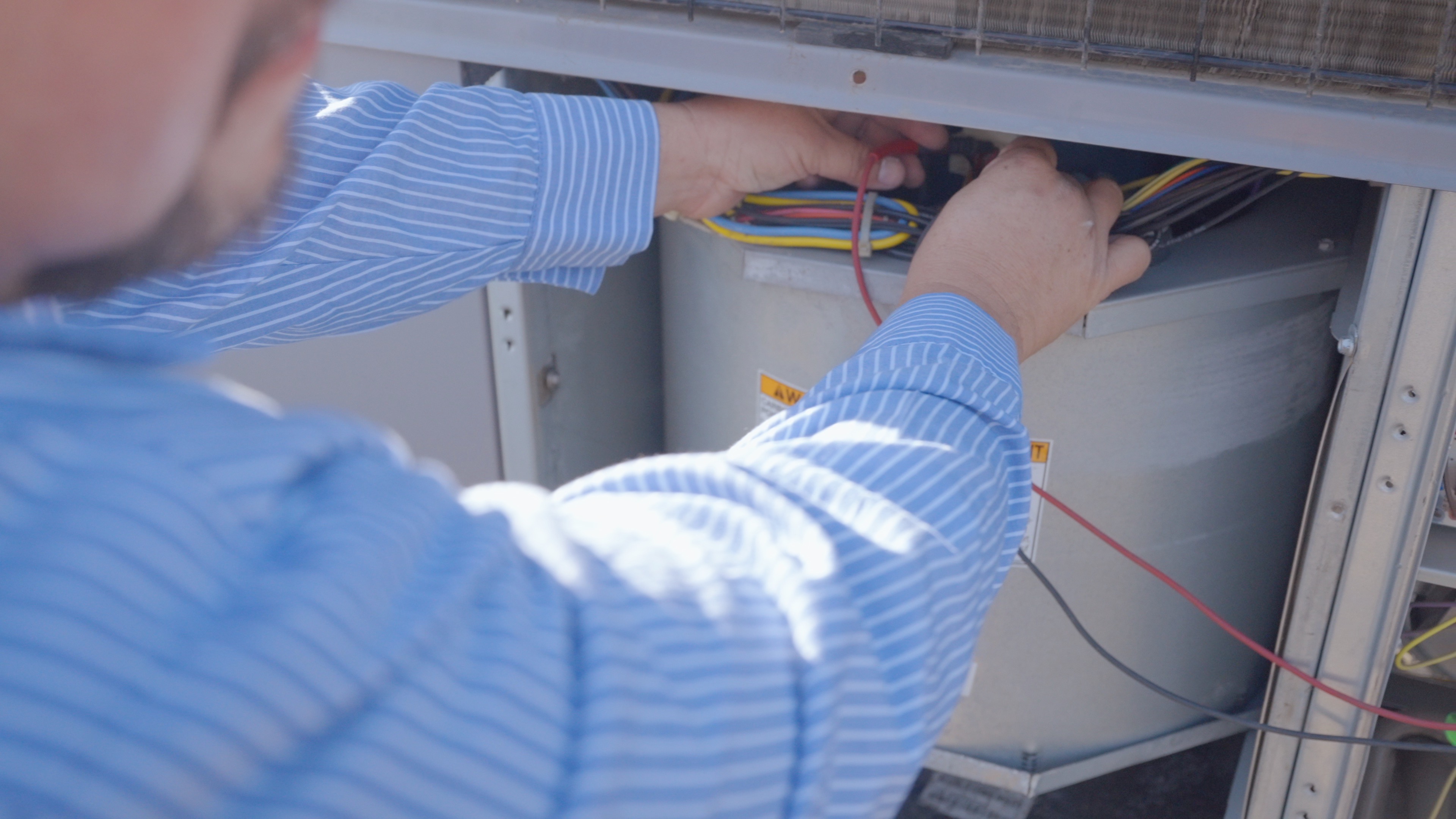 Technician Ben working on an outdoor HVAC unit to ensure efficient performance
